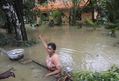 Una mujer varada gesticula hacia su casa mientras pide ayuda a voluntarios, el 19 de agosto de 2018, en Chengannur, Kerala.