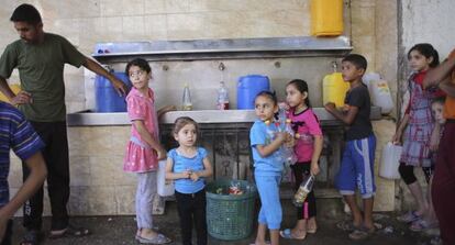 Ni&ntilde;os palestinos hacen cola para rellenar botellas de agua en Rafah. 