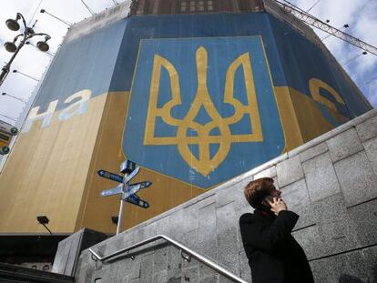 Un hombre habla por tel&eacute;fono junto a un edificio decorado con los colores nacionales junto a la plaza Maid&aacute;n en Kiev, este martes.