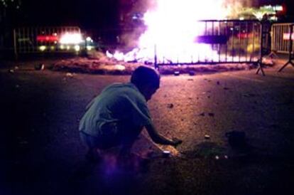 Un niño enciende petardos ante una de las hogueras de la noche de Sant Joan.