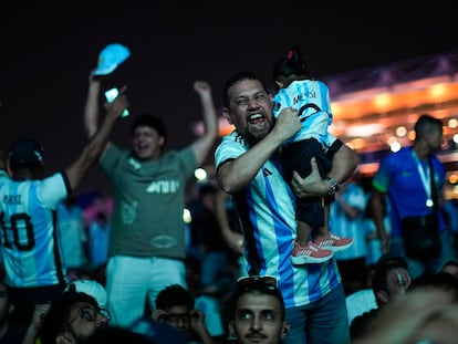 Un hombre, con su hija en manos, celebra el gol de Messi en las afueras del estadio Lusail, en Doha.
