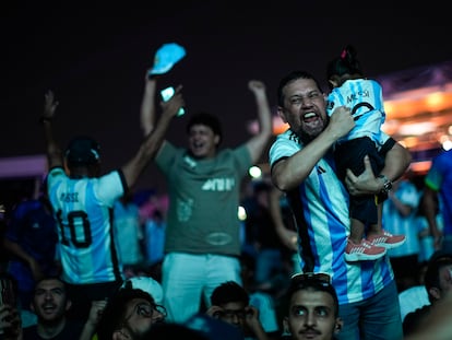 Un hombre, con su hija en manos, celebra el gol de Messi en las afueras del estadio Lusail, en Doha.