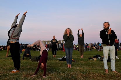 Un grupo de personas hacen yoga mientras esperan el comienzo del solsticio de verano en Stonehenge, en Salisbury (Reino Unido).