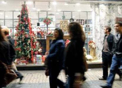 Unas personas pasan por delante de un escaparate de un comercio situado en una gran superficie. EFE/Archivo