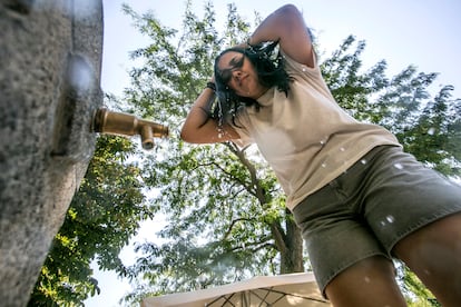 Una mujer se moja la cabeza durante la ola de calor en una fuente de Madrid, este miércoles.