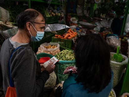 Una pareja compra verduras en un mercado en Bogotá.