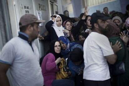 Un grupo de mujeres refugiadas busca refugio junto al control de policía del puerto.