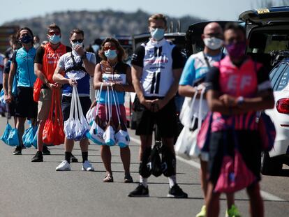 Auxiliares de equipos esperan para dar bolsas de avituallamiento a los ciclistas en una etapa del Tour de 2020.