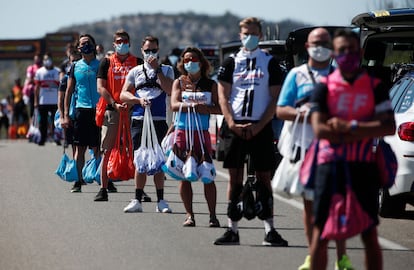 Auxiliares de equipos esperan para dar bolsas de avituallamiento a los ciclistas en una etapa del Tour de 2020.