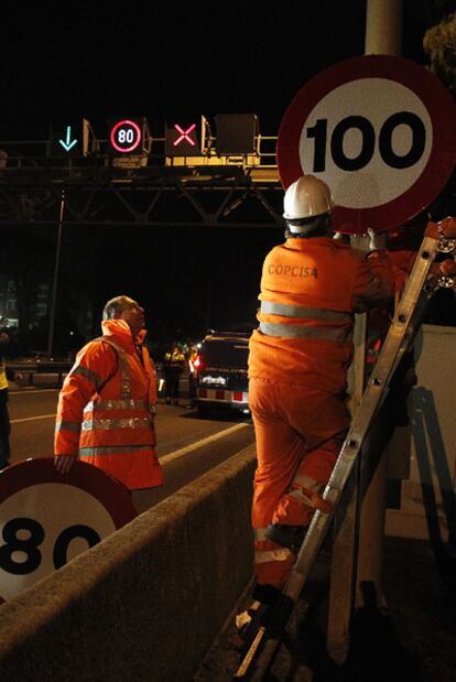 Unos operarios cambian las señales de límite de velocidad en la autovía de Castelldefels.