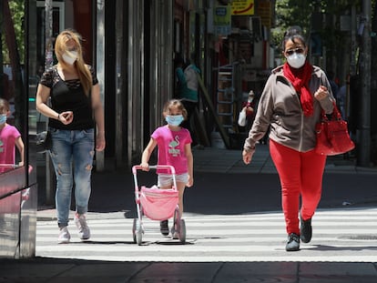 Adultos y niños pasean con mascarillas en Madrid.