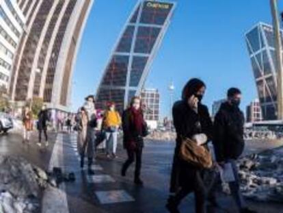 Peatones cruzan una calle en Plaza de Castilla en Madrid, este martes.