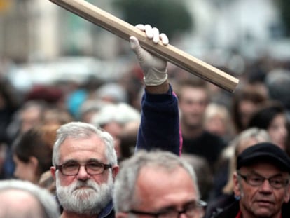 Homem segura lápis gigante durante uma manifestação na França.