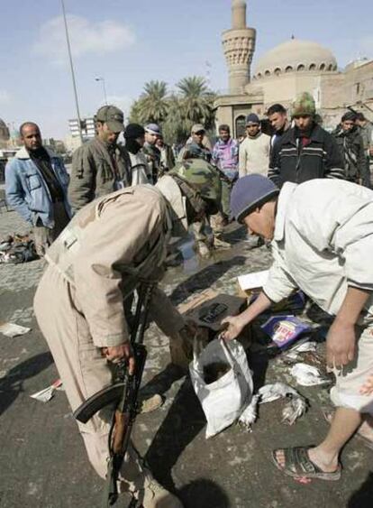 Un soldado y un civil iraquíes sostienen una bolsa con los restos de una de las suicidas.
