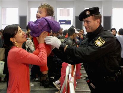 Un policía ayuda en la estación de tren de Munich a una madre refugiada recién llegada desde Salzburgo, este sábado 5 de septiembre.