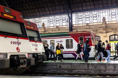 Varias personas pasaban el lunes junto a trenes de cercanías en la Estación del Norte de Valencia.