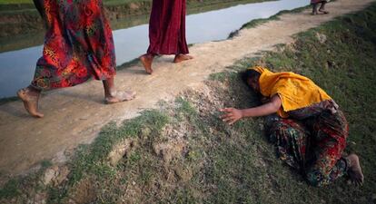 Una mujer rohingya agotada pide ayuda a otros refugiados mientras continúan su camino después de cruzar la frontera de Myanmar y dirigirse a Cox's Bazar (Bangladés).