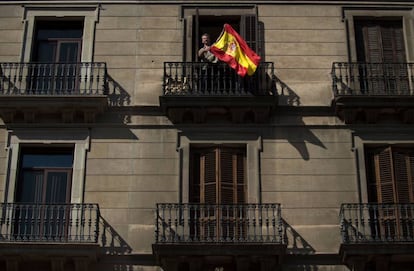 Un hombre ondea una bandera de España en un balcón durante la manifestación convocada en Barcelona el 8 de octubre.