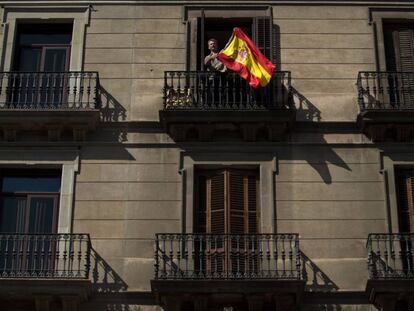Un hombre ondea una bandera de España en un balcón durante la manifestación convocada en Barcelona el 8 de octubre.