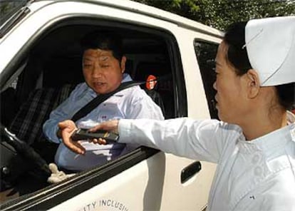 Una enfermera toma la temperatura a un conductor antes de su entrada a un hospital de Pekín.