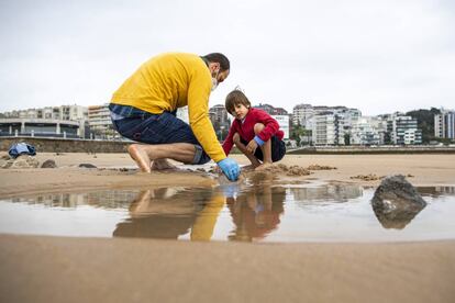 Uma criança brinca com seu pai em uma praia de Santander.