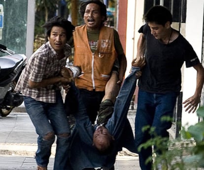 Tres hombres trasladan a un <i>camisa roja</i> herido por los disparos de un soldado tailandés.