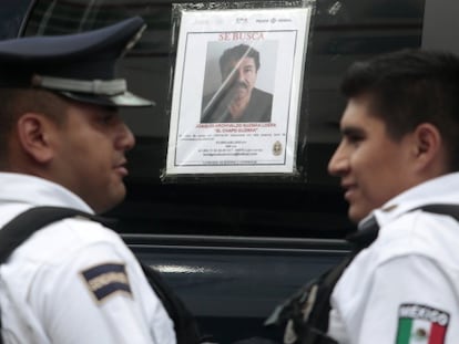 Dos polic&iacute;as ante el cartel de b&uacute;squeda de Guzm&aacute;n.