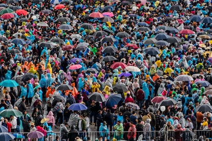 El público se resguarda de la lluvia con paraguas y ponchos.