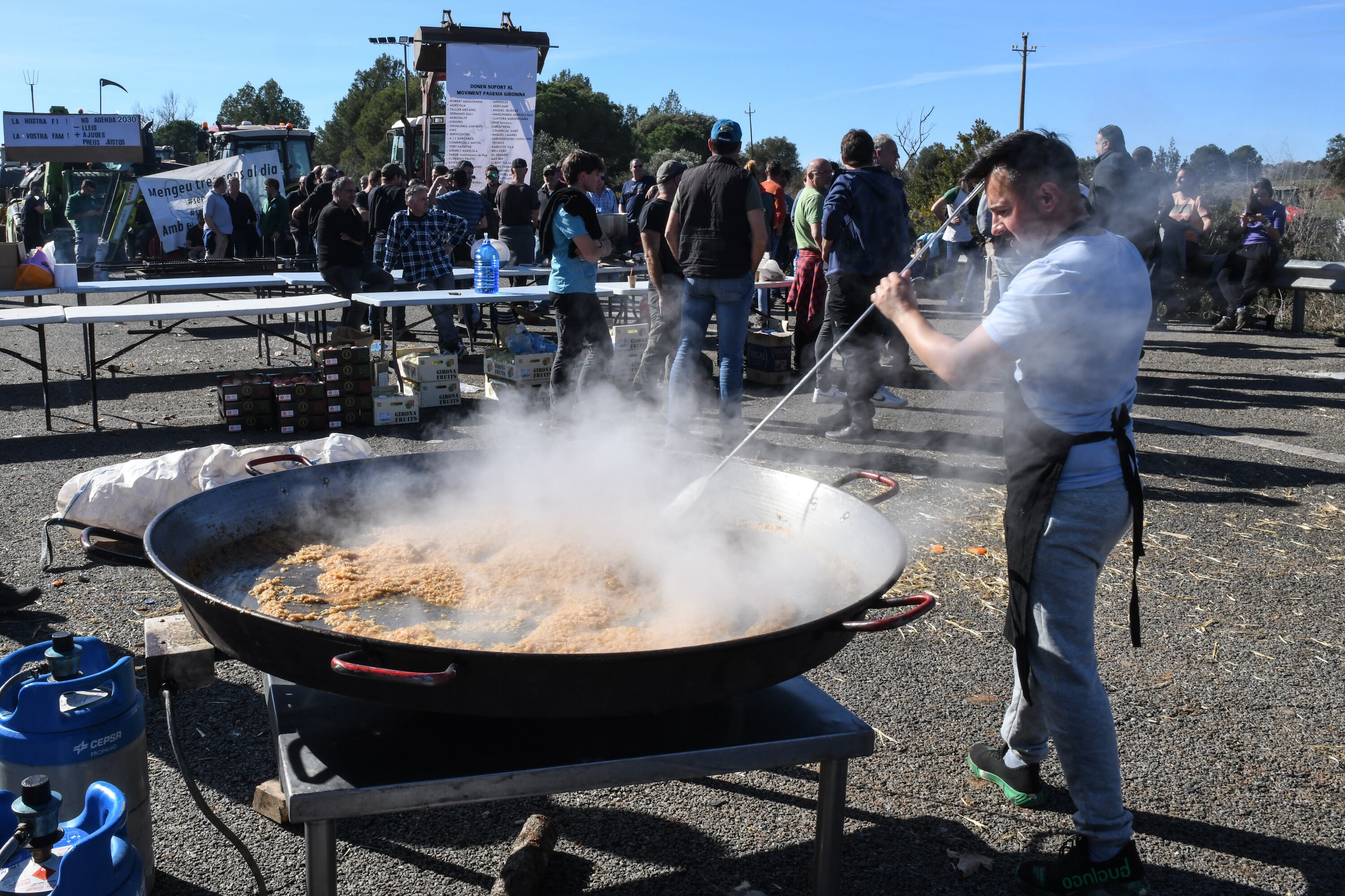 Un agricultor prepara la comida en una paellera gigante, mientras los tractores bloquean la autopista AP-7 a la altura de Pontós, este miércoles.