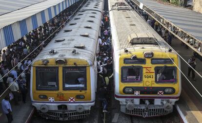 Un grupo de trabajadores se afana por subirse al tren en una estación de Bombay (India).