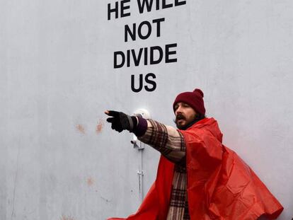 El actor Shia LaBeouf, con poncho naranja, junto a su instalación 'Él no nos dividirá'.