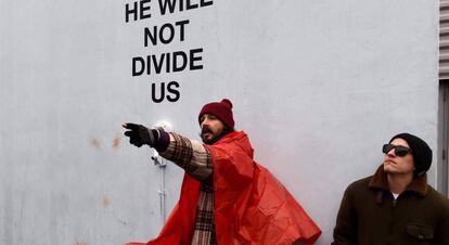 El actor Shia LaBeouf, con poncho naranja, junto a su instalación 'Él no nos dividirá'.