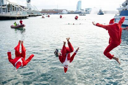 Participantes disfrazados de Papá Noel saltan al agua durante la 111ª edición de la carrera de natación Copa Nadal en el Port Vell de Barcelona.