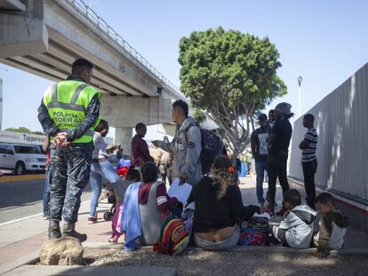 Mujeres y niños, junto a la barda de la garita fronteriza donde se atiende la lista de asilo.