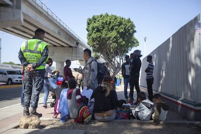 Mujeres y niños, junto a la barda de la garita fronteriza donde se atiende la lista de asilo.