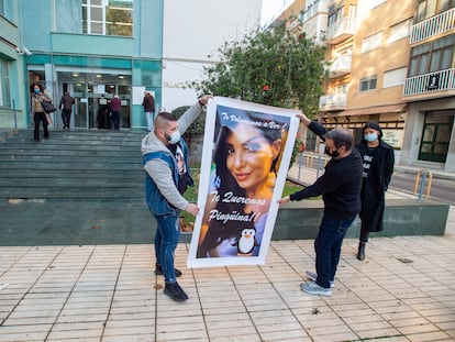 Dos familiares portan un cartel de Sara Gómez, la mujer fallecida tras una cirugía estética, este martes frente a los juzgados de Cartagena.