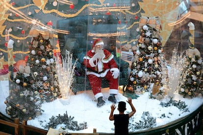 Abilio Nunes, artista do Papai Noel, acena para crianças de dentro de uma bolha, em um shopping de Brasília.