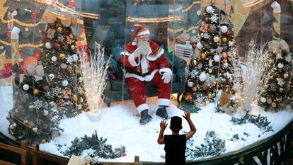 Abilio Nunes, artista do Papai Noel, acena para crianças de dentro de uma bolha, em um shopping de Brasília.