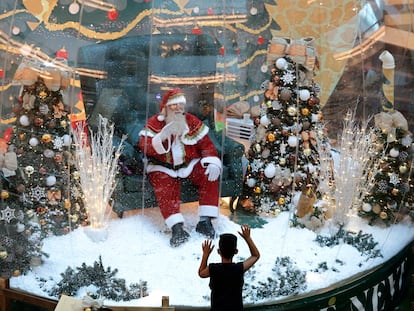 Abilio Nunes, artista do Papai Noel, acena para crianças de dentro de uma bolha, em um shopping de Brasília.