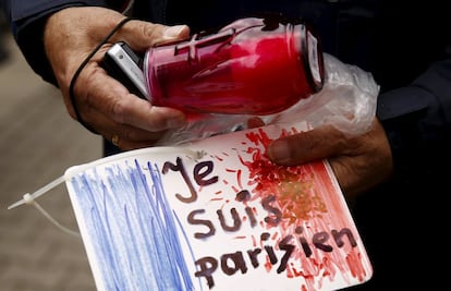 Homem segura um cartaz "Eu sou parisiense" em frente à embaixada da França na Polônia.