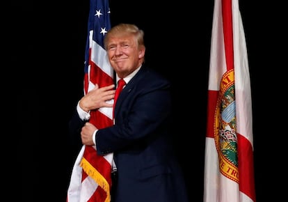 Donald Trump agarra una bandera de los Estados Unidos al inicio de un acto de campaña en Tampa, el 24 de octubre de 2016.