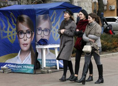 Tres jóvenes caminan delante de un puesto electoral de Yulia Timoshenko en Kiev.