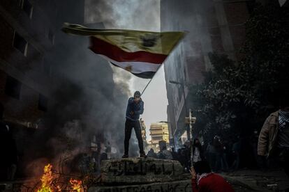 Un manifestante egipcio levanta una bandera sobre una barricada durante los enfrentamientos con la policía.