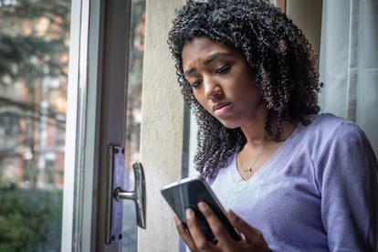 Una adolescente observa su celular en casa.