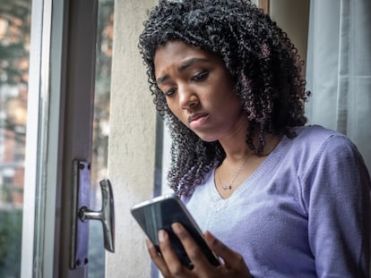 Una adolescente observa su celular en casa.