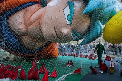 Un trabajador pasa debajo del inflable de Goku, el personaje de la serie de animación japonesa 'Dragon Ball'.