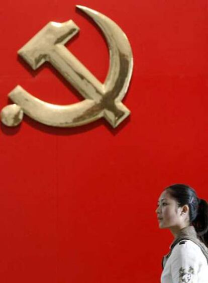 Una mujer pasa junto al emblema del Partido Comunista Chino en el Museo Militar de Pekín.