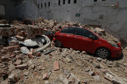 Vários carros ficaram soterrados entre os restos de um edifício derrubado pelo terremoto.