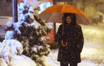 Una mujer camina con una sombrilla sobre una calle cubierta de nieve en Belgrado, Serbia. EFE/Archivo