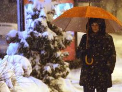 Una mujer camina con una sombrilla sobre una calle cubierta de nieve en Belgrado, Serbia. EFE/Archivo